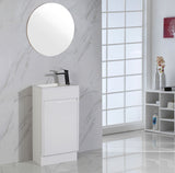 Bathroom vanity with round mirror and black faucet against a marble wall.