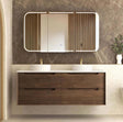 Bathroom vanity with wooden cabinets, white countertop, and mirror on a marble wall.