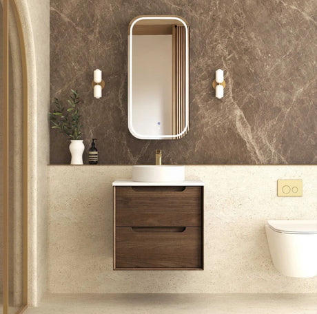 Bathroom with wooden vanity, mirror, and toilet against a marble wall.