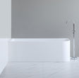 White freestanding bathtub with a silver faucet against a gray wall.