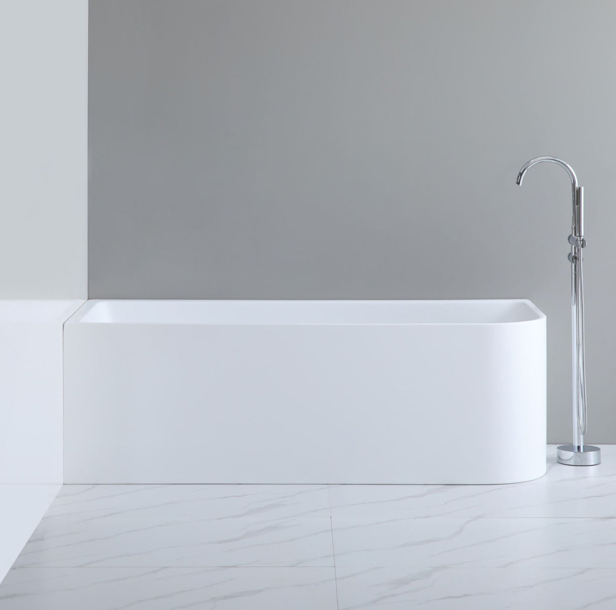 White freestanding bathtub with a silver faucet against a gray wall.