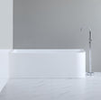 Modern freestanding bathtub in a minimalistic bathroom setting with a gray wall and white floor.