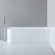 Modern freestanding bathtub in a minimalistic bathroom setting with a gray wall and white floor.