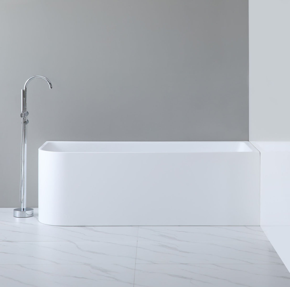Modern freestanding bathtub in a minimalistic bathroom setting with a gray wall and white floor.
