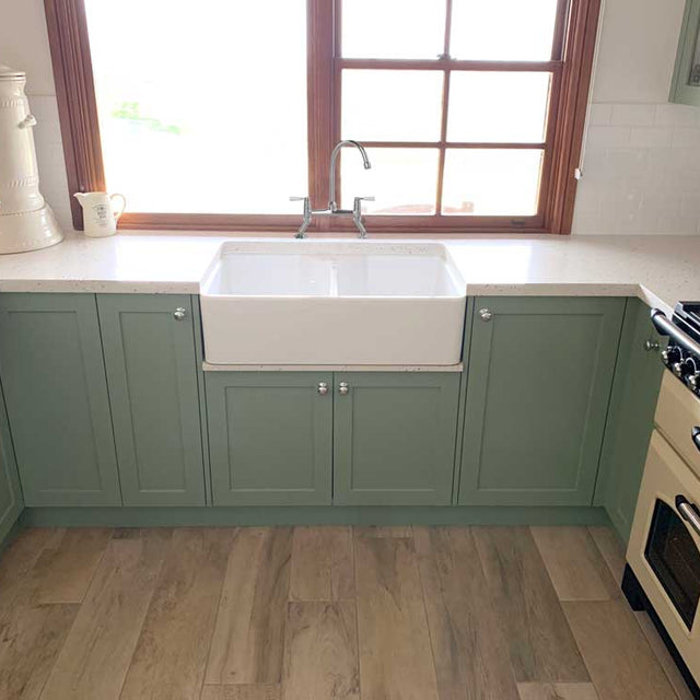 Kitchen with green cabinets, white countertop, and wooden floor.