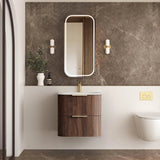 Bathroom with wooden vanity, mirror, and toilet against a marble wall.
