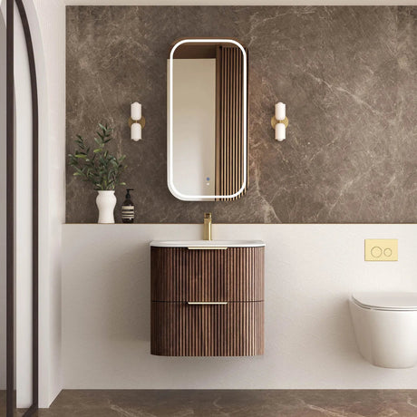 Bathroom with wooden vanity, mirror, and toilet against a marble wall.