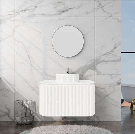White bathroom vanity with round mirror against a marble wall