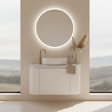 Bathroom vanity with round mirror and decorative elements against a scenic window backdrop