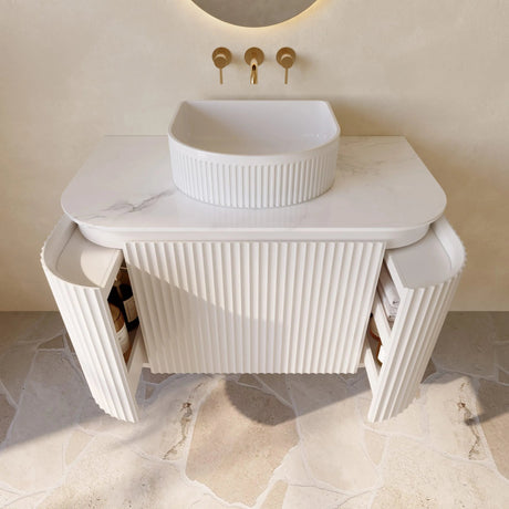 Modern bathroom vanity with a white sink and gold fixtures.