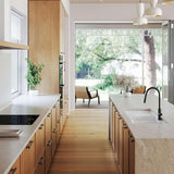 Modern kitchen with wooden cabinets, white countertops, and a view of greenery outside.
