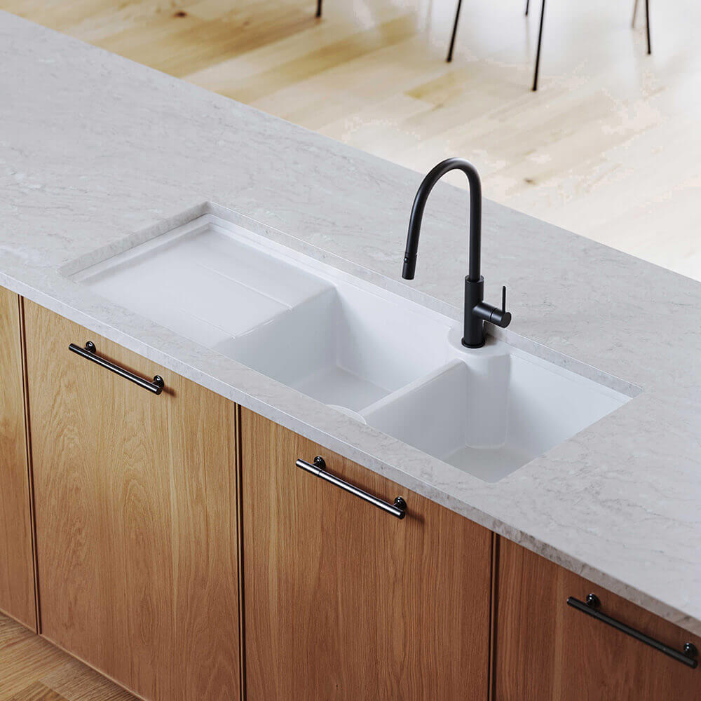 White kitchen sink with black faucet on a countertop with wooden cabinets.