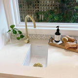 Kitchen sink with gold faucet and window view