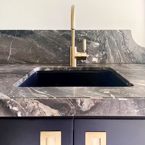 Marble countertop with a sink and gold faucet
