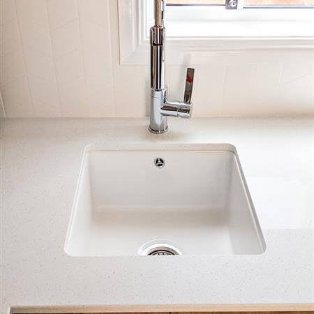 White kitchen sink with silver faucet in a modern kitchen setting