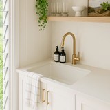 Modern kitchen with a sink, gold faucet, and shelves with decor items.
