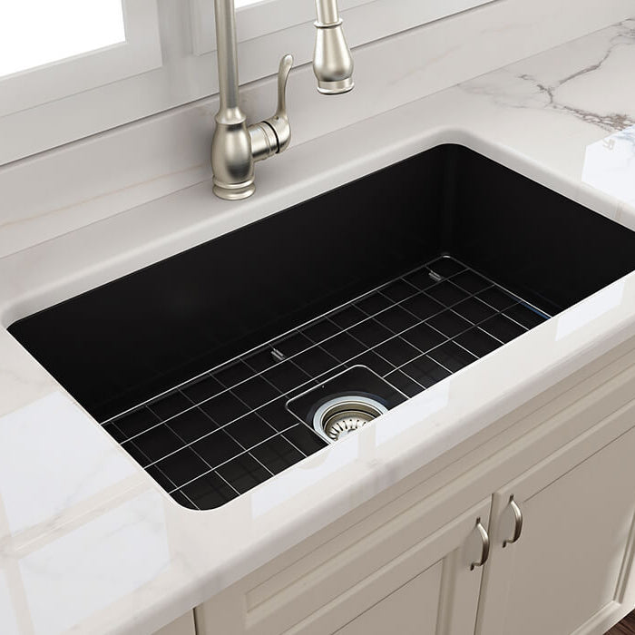 Black farmhouse kitchen sink with silver faucet in a modern kitchen setting.