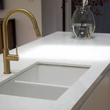 Modern kitchen sink with gold faucet and white countertop