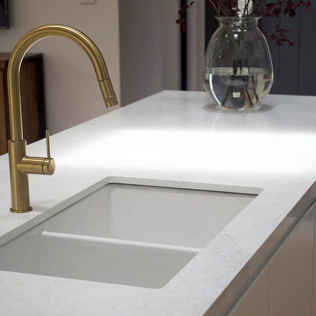 Modern kitchen sink with gold faucet and white countertop