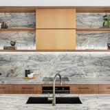 A modern kitchen interior featuring a large marble-patterned backsplash and matching marble countertop, with warm wood cabinetry and open shelving displaying decorative objects.