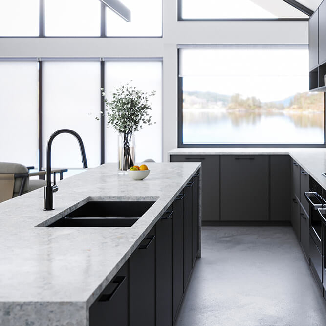 Modern kitchen with black cabinets, white countertops, and a view of water through large windows.