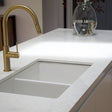 Modern kitchen sink with gold faucet and white countertop