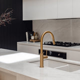 Modern kitchen with a gold faucet over a sink, black stove, and white cabinets.