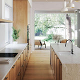 Modern kitchen with wooden cabinets, white countertops, and a view of greenery outside.