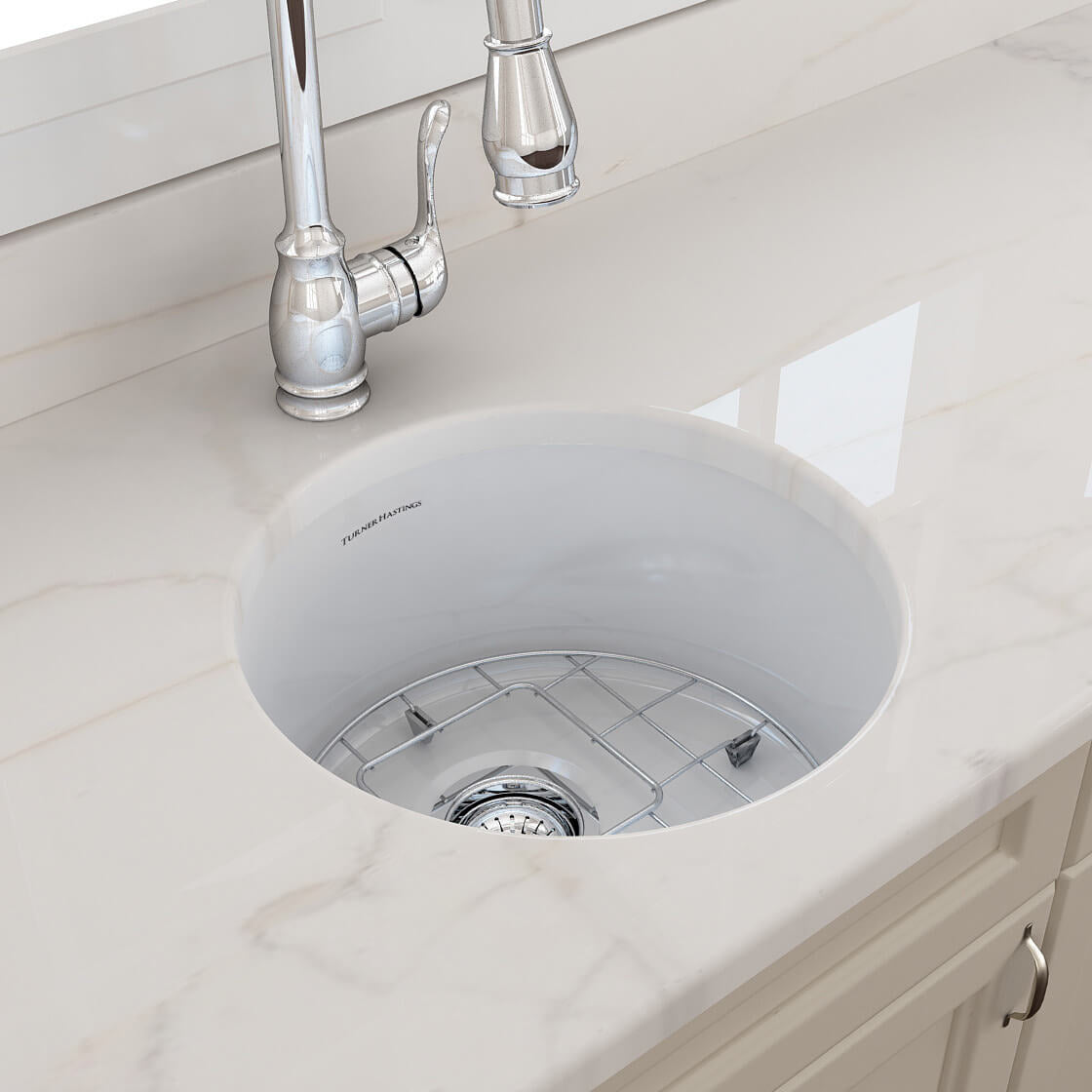 White kitchen sink with silver faucet on a marble countertop