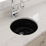 Black kitchen sink with chrome faucet on a white marble countertop