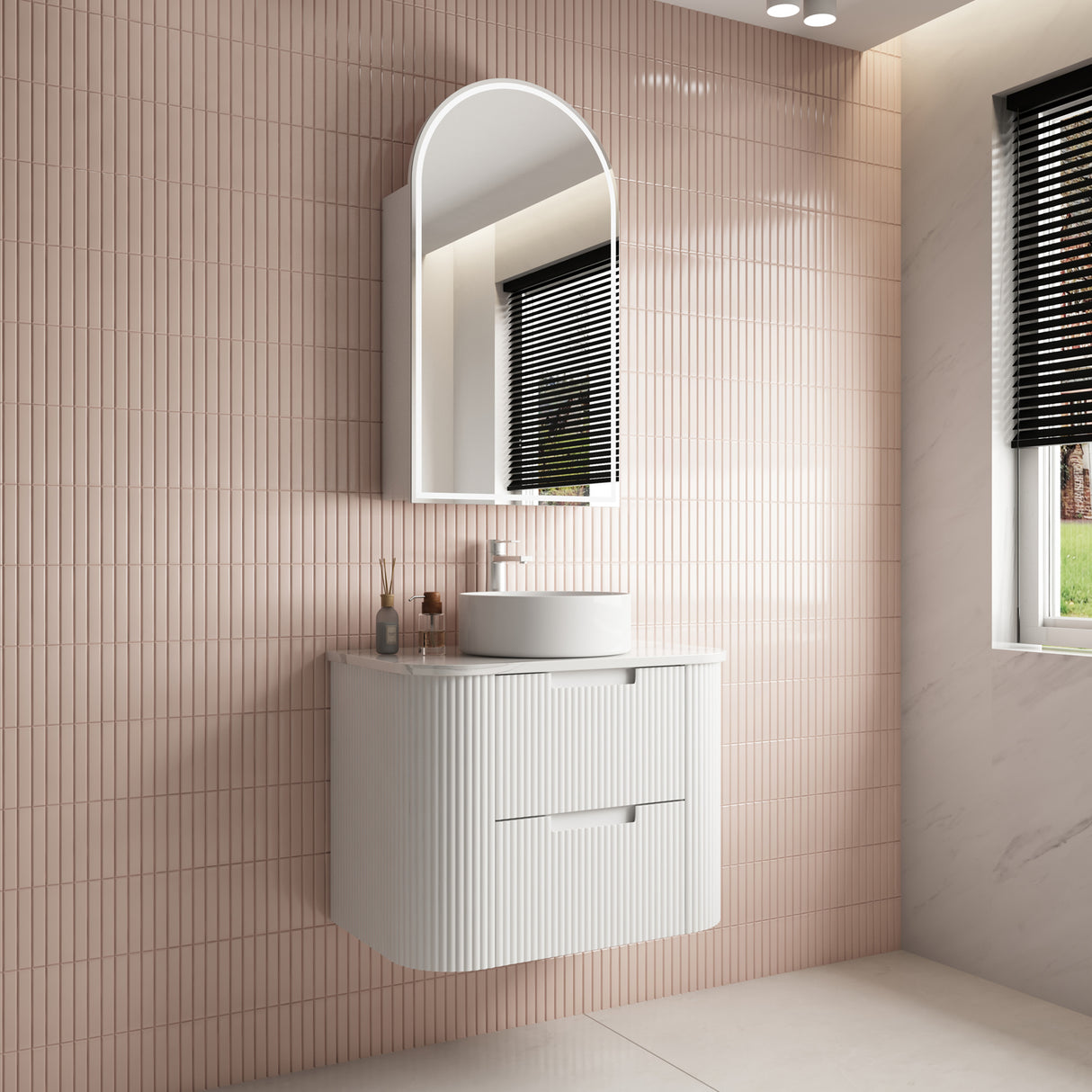 Bathroom with a white vanity unit, sink, and mirror against a tiled wall.
