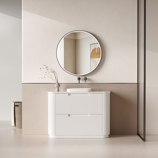 Modern bathroom vanity with round mirror and decorative elements.