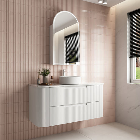 Bathroom vanity with sink and mirror against a tiled wall.
