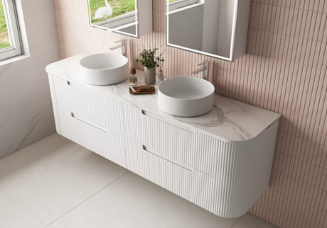 Bathroom vanity with two white sinks and a mirror in a tiled bathroom.