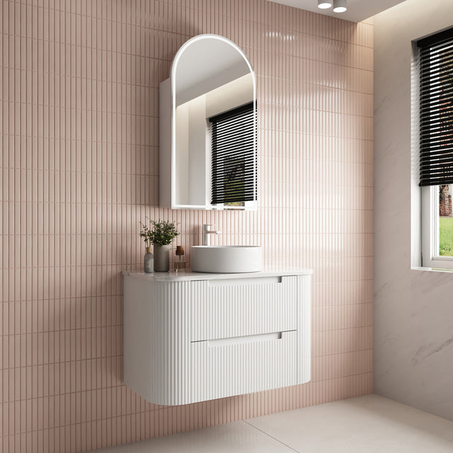 Bathroom vanity with sink and mirror against a tiled wall.