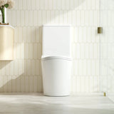 Modern white toilet in a bathroom with light wood flooring and tiled walls.