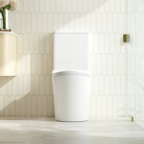 Modern white toilet in a bathroom with light wood flooring and tiled walls.