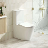 Modern white toilet in a bathroom with marble walls and gold fixtures
