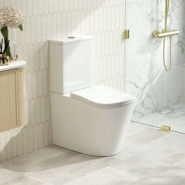 Modern white toilet in a bathroom with marble walls and gold fixtures