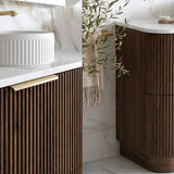 Modern bathroom vanity with fluted dark wood cabinets, white marble countertops, a white vessel sink, and a gold faucet, shown alongside a matching vanity unit.