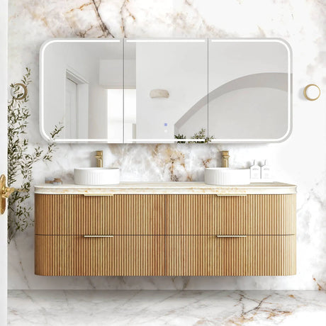 Bathroom vanity with wooden cabinet, marble countertop, and large mirror against a marble wall.
