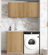 A modern laundry room setup featuring a white front-load washing machine integrated into a slatted wood cabinet, set against a white marble backsplash and light wood flooring.