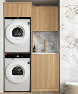 Laundry room with stacked washer and dryer under wooden cabinets against a marble wall.