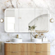 Bathroom vanity with wooden cabinets, white countertop, and large mirror on marble wall.