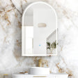Bathroom with a marble wall, sink, and arch-shaped mirror.
