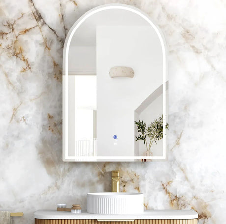 Bathroom with a marble wall, sink, and arch-shaped mirror.