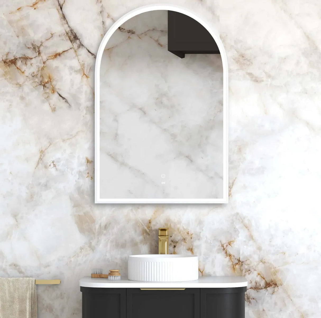 Bathroom with marble wall, white sink, and arch-shaped mirror.