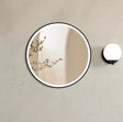 Round mirror with black frame on a beige wall