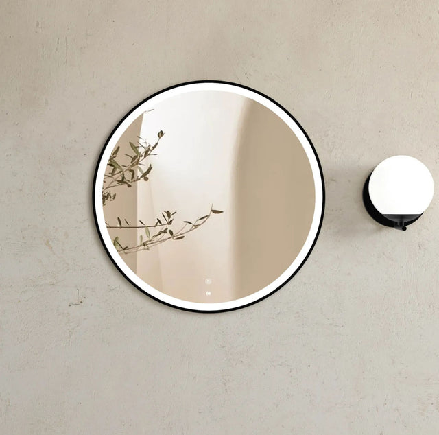Round mirror with black frame on a beige wall