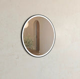 Round wall mirror with black frame on a beige wall